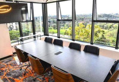 Modern conference room with a dark wood table and large windows overlooking lush greenery.