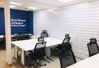 Open-plan office with white desks and a blue feature wall with inspirational text.