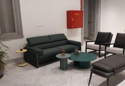 Modern lounge area with a dark green sofa, circular coffee tables, and a red fire cabinet.