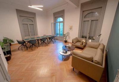 Meeting room with a long glass-top table, dark blue chairs, and tan leather sofas.