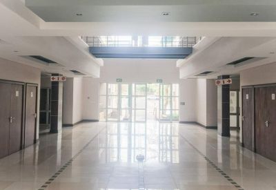 Bright, spacious lobby with white tile floors and glass double doors leading outside.