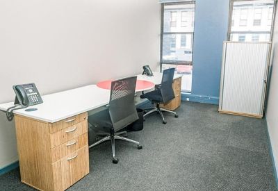 Two-person private office with wooden desks and grey ergonomic chairs.