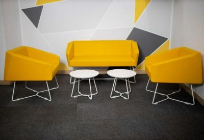 Modern lounge area with bright yellow armchairs and geometric wall art.