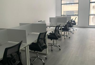 Open-plan office with white desks and black ergonomic chairs.