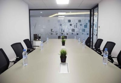 Professional conference room with a long white table, black mesh chairs, and frosted glass walls.