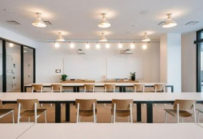 Bright training room with long white tables and wood-backed chairs.