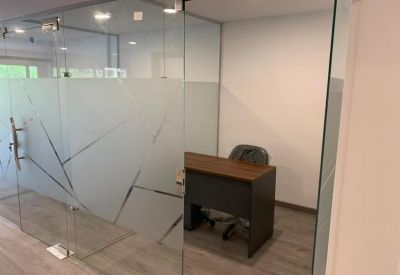 Private glass-walled office suite with a dark wood desk and frosted geometric patterns.