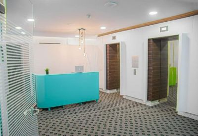 Bright reception area featuring a vibrant turquoise front desk and patterned grey carpet.