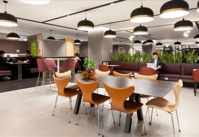 Communal dining and workspace area with designer chairs and stylish pendant lighting.