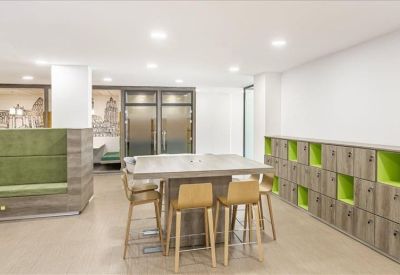 Breakout area featuring a high table with wooden stools and integrated storage lockers.