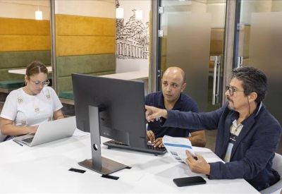 Coworking space with professionals collaborating at a computer and laptop.