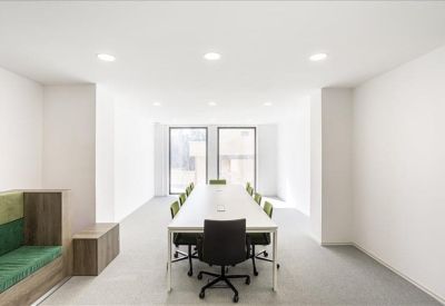 Long boardroom table with black chairs in a bright, white meeting room.