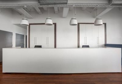 Minimalist white reception desk under modern pendant lighting with a wood floor.