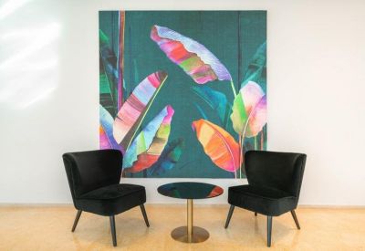 Lounge area featuring black velvet armchairs and colorful botanical wall art.