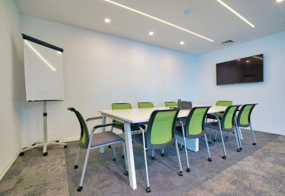 Bright meeting room with a long white table and lime green mesh chairs.