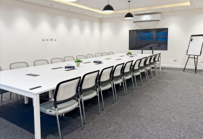 Spacious boardroom at Business Hub, Cairo International Airport with a long white table and video conferencing screen.