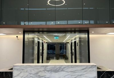 Modern lobby featuring a marble reception desk under a tiered circular chandelier.