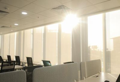 Bright open-plan office with rows of white desks and ergonomic black chairs.