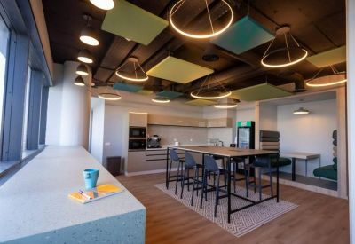 Modern communal kitchen and breakout area with high tables and industrial lighting.