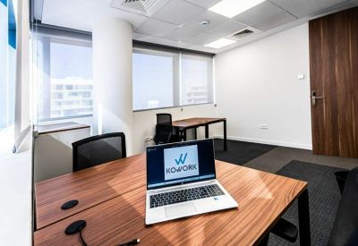 Private office suite with wooden desks and large windows offering natural light.
