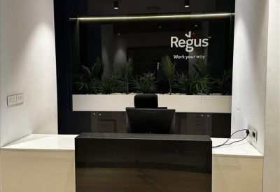 Modern black and white reception desk with integrated greenery and corporate branding.