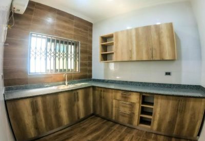 L-shaped kitchen featuring wood-grain cabinetry and dark stone countertops.
