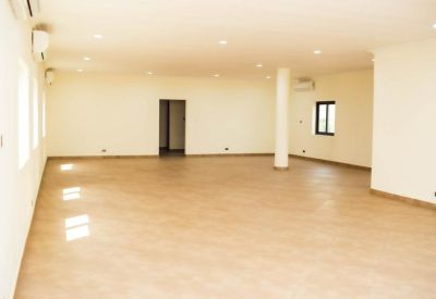 Spacious open-plan office area with neutral tiled flooring and white walls.