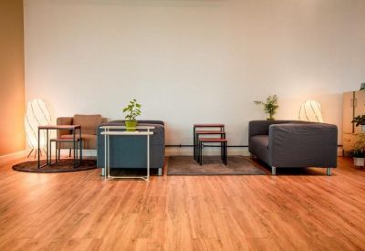 Spacious breakout lounge with modern grey sofas and wooden flooring.