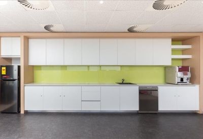Bright communal kitchen area with white cabinetry and a lime green backsplash.