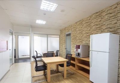 Breakout area and kitchen with a stone-textured wall, dining table, and full-sized refrigerator.