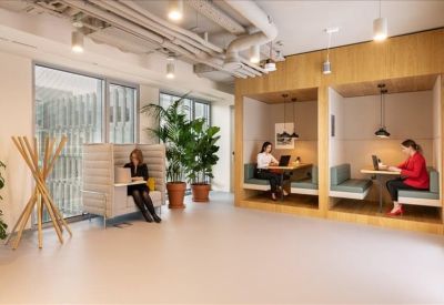 Semi-private working booths lined with wood panels and featuring indoor plants.