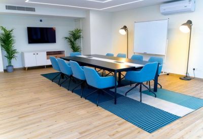 Modern meeting room featuring a long dark table, blue chairs, and whiteboard.