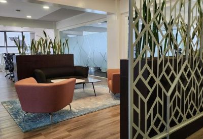 Reception lounge area with orange chairs and a decorative geometric partition screen.