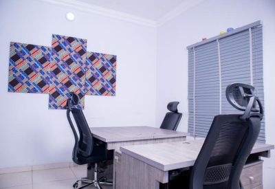 Private office suite featuring two wooden desks and ergonomic black chairs against a white wall.