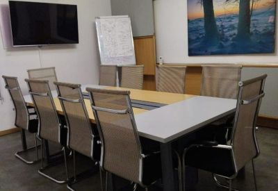Spacious meeting room with a long table, modern mesh chairs, and a scenic wall mural.