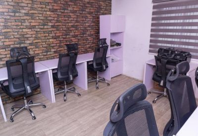 Open-plan office with multiple workstations against a rustic brick feature wall.