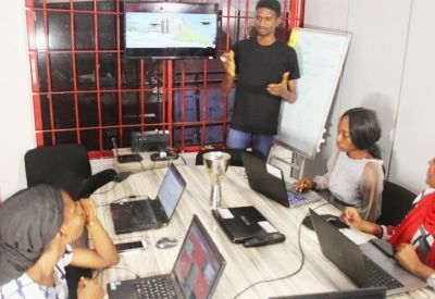 Modern collaborative workspace featuring a round table, laptops, and a presentation screen.