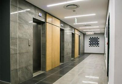 Bright elevator lobby with stone-cladding walls and light wood panel accents.