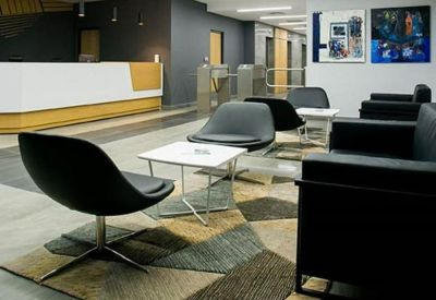 Modern reception lounge with stylish black armchairs and a geometric patterned rug.