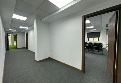 Clean office corridor with grey carpeting leading to a meeting room doorway.
