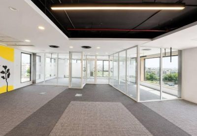 Bright workspace featuring glass-partitioned offices and a yellow accent wall with leaf art.