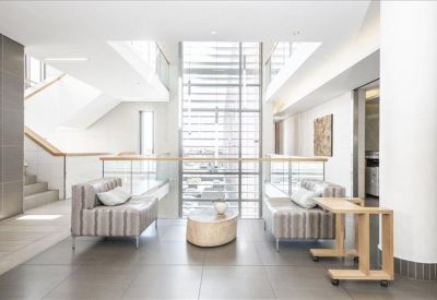 Spacious sun-drenched lobby area with modern striped sofas and a glass staircase.