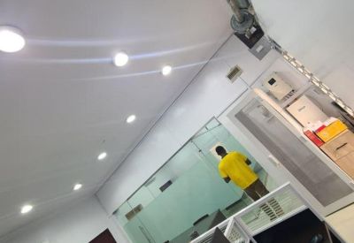 Brightly lit modern office interior with white walls, glass partitions, and recessed ceiling lights.