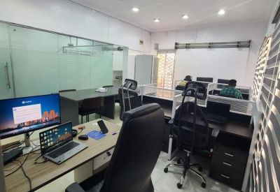Executive office area with a light-toned wood desk, professional rolling chairs, and glass wall dividers.