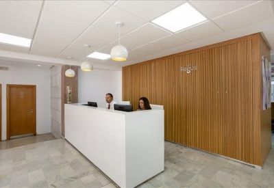 Bright reception area featuring a minimalist white desk and warm wood paneled wall.
