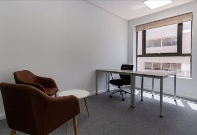 Bright private office suite with a white desk and brown accent chairs.