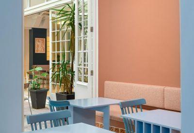 Lounge area with light blue and terracotta walls, featuring blue wooden tables.