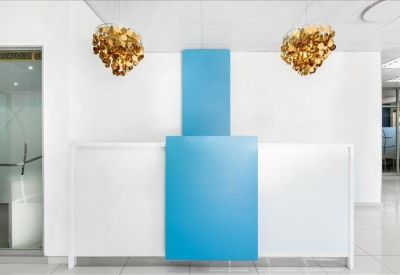 Sleek reception area featuring a white and blue front desk under designer pendant lights.