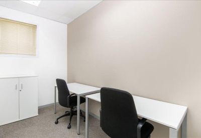 Two-person private office suite with white desks and black chairs.