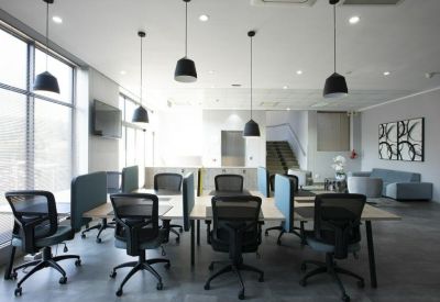 Bright coworking area with several workstations and pendant lighting.